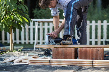 Man using saw to cut wooden planks