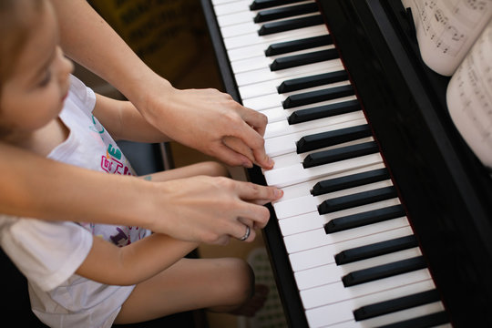Little girl being taught playing piano