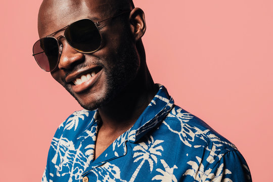 Portrait Of Handsome Black Man Looking At Camera With Sunglasses Over Light Pink Background