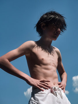 Portrait of a teenager with wet hair against a blue sky