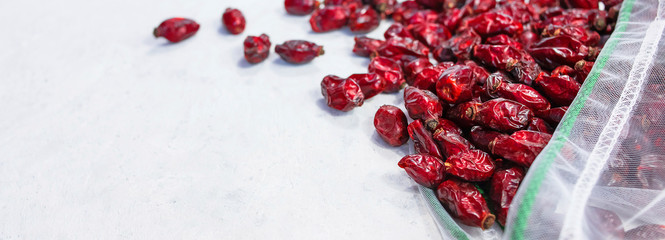 Dried rose hips in mesh bag on white background