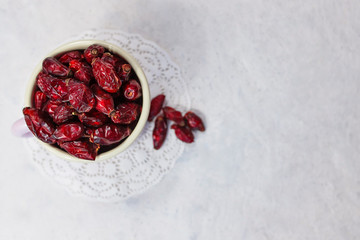 Dried rose hips in enameled mug top view on white background