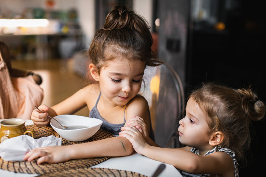 Little girl bothering her sister having soup at table