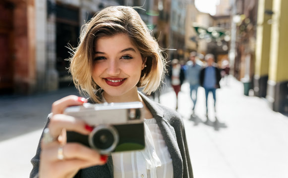 Blonde woman taking a picture on the street