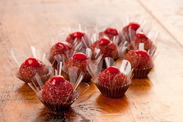 Cherry and chocolate handmade truffles on wooden background.