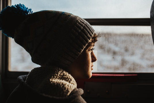 Close up of boy looking through window while traveling by bus