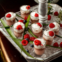 chocolate pudding topped with whipped cream and raspberry in shot glasses