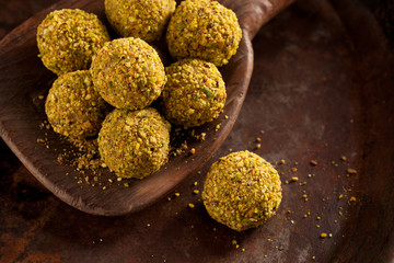 Handmade pistachio chocolate truffles on wooden background.