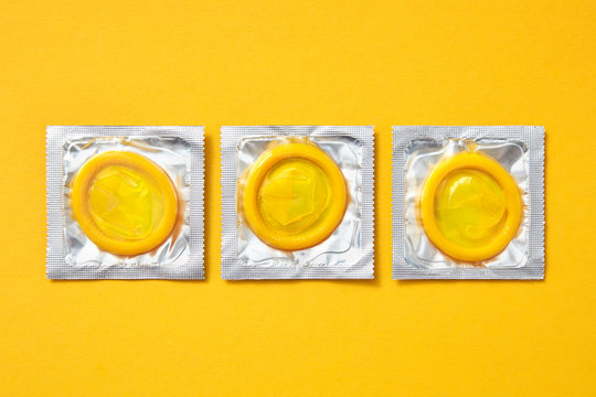 Three yellow condoms on an yellow.