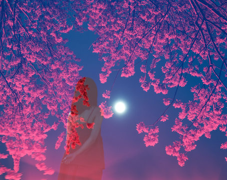 Woman looking at moon among red flowers at night