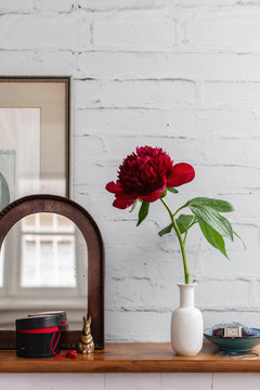 Mirror and painting on wooden shelf with feminine objects like jewels and clock