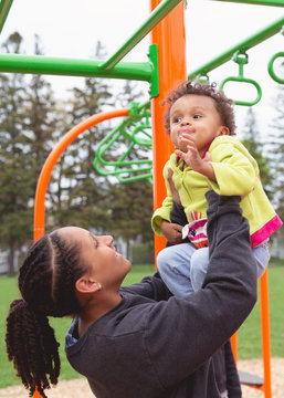 Pretty smiling toddler girl being lifted into the air by her smiling teen sister.