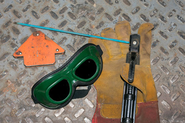 welding machine, in the workshop, welding mask, leather gloves, welding electrodes, high-voltage wires with clips, a set of accessories for arc welding.