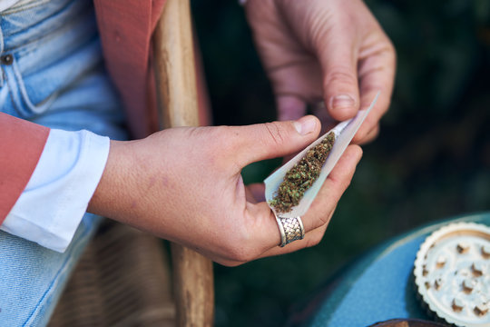 closeup of female hands rolling a cannabis cigarette