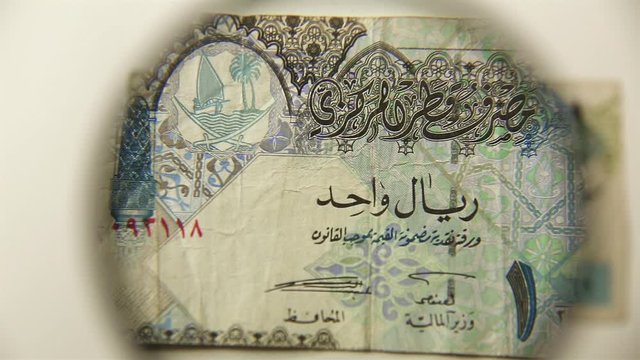 One Qatar riyal and a magnifying glass. View a paper bill through a magnifying glass. reverse.