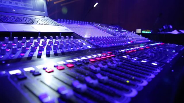Electric machine on table for working of sound designer or club dj at party in nightclub in neon blue and violet lighting.Occupation for modern lifestyle, objects for listen at background. 