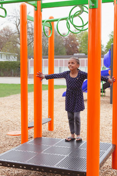 Young mixed child preparing to run and jump onto the monkey bars at a playground