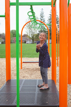 Young mixed child standing on the playground equipment and laughing happily
