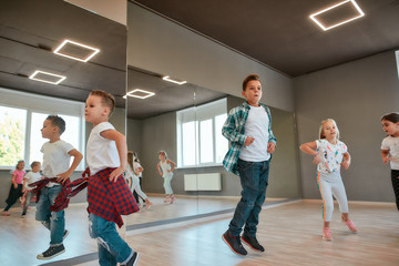 Fototapeta premium Full of energy. Little happy boys and girls running and jumping in the dance studio. Warming up before dance class