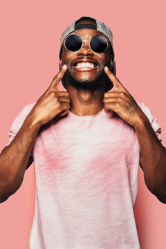 Happy young black man laughing at camera over pink background