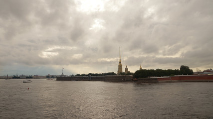 Peter and Paul Fortress is one of the attractions in the city of St. Petersburg in Russia. The evening sky is reflected in the Neva River, pleasure excursion boats sail by.