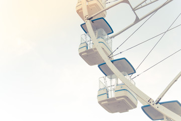 Blue, light, white, sky, ferris wheel. Ferris wheel and piece sunlight. Vintage style. Close-up.