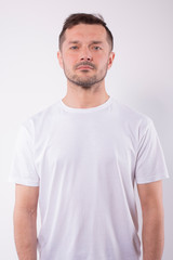 Fototapeta premium Caucasian man with brown hair in casual t-shirt stands straight, looks at camera