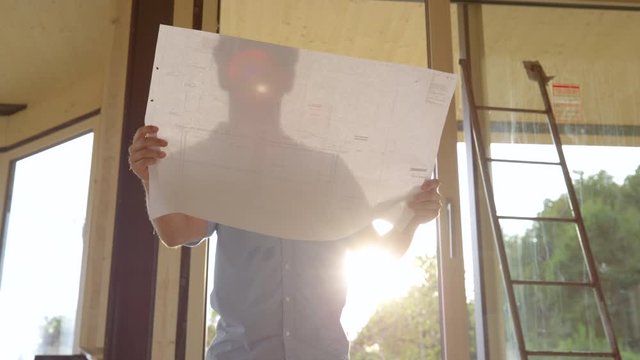 SLOW MOTION, LENS FLARE, CLOSE UP: Investor Looks At The Floor Plans While Analysing The Progress At The Construction Site Of A Real Estate Project. Head Contractor Goes Over The Blueprints And House.