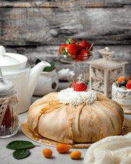 crepe cake in bundle shape topped with cream and strawberry