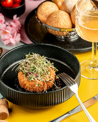 crispy breaded chicken patty topped with herbs in black bowl