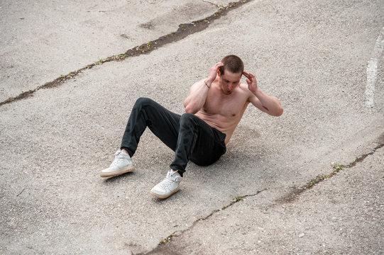 powerful street work-out of the crossfit athlete - doing sit-ups in the playground