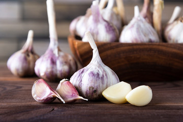 Bulbs and cloves of garlic in a vintage wooden bowl on a dark background