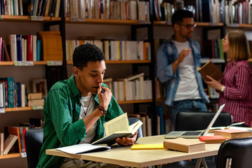 Young male student study in the library reading book.