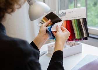 A view of a female artisan comparing fabric samples in her atelier.