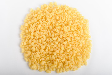 Heap of dried cornetti rigati traditional Italian pasta on a plate ready to be cooked, isolated on a white table, top view or flat lay of healthy food 
