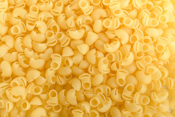 Heap of dried cornetti rigati traditional Italian pasta on a plate ready to be cooked, isolated on a white table, top view or flat lay of healthy food 
