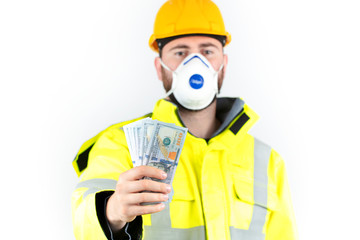 young engineer holds dollars in hands. Worker wearing a mask against the danger of a deadly virus. world economic crisis and job loss concept.