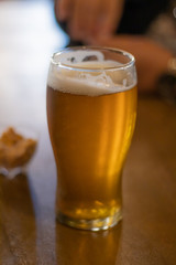 Cerveza en mesa de madera con maní en un recipiente de fondo