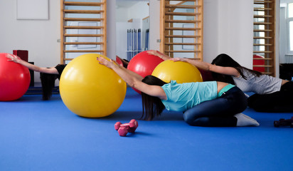 Group of young female models doing stretching workout on pilatess balls