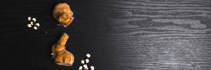 Fototapeta premium chocolate willow branches and cute bunnies on wooden background