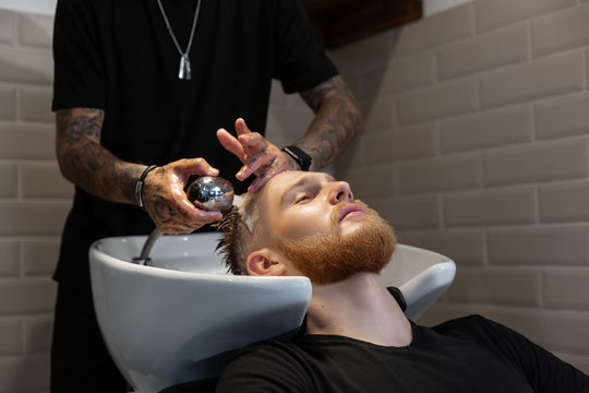 Barber washing hair of customer in sink at salon