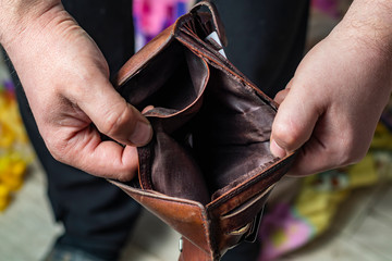 retro style wooden background. Human hands open a wallet of cinnamon color. Lack of money concept.