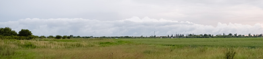 Cloudy landscape, village before the rain, visible large cumulus clouds and clouds over the village.