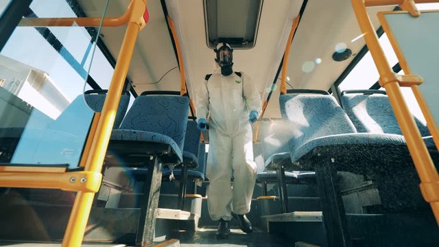 Coronavirus prevention, epidemic concept. Disinfection expert is walking along the bus and sanitizing it