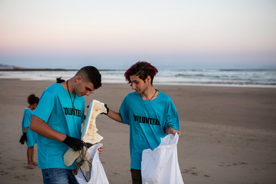 Two teenagers collecting trash from the beach