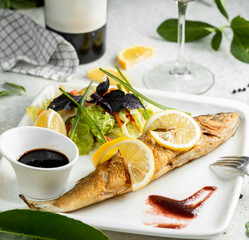 fried fish garnished with lemon slices served with salad and nar sharab
