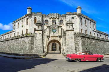 Havana Cuba Pink vintage classic american car near Real Fuerza Castle typical colorful street with sunny blue sky 