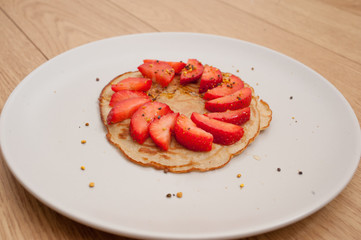 strawberry pancake on a white plate in a wooden table