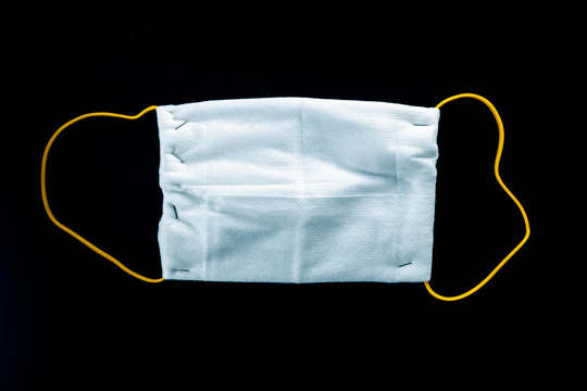 Dettaglio di una mascherina chirurgica fatta in casa a mano per il Coronavirus con cotone, spille di una pinzatrice ed elastico. Sfondo nero. Vista macro.