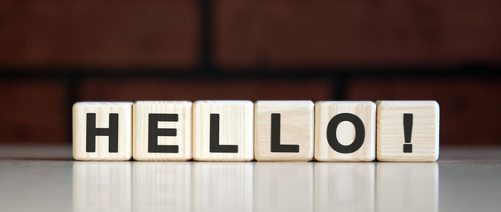 HELLO - HI concept on on a dark brick background. Wooden cubes with text © Aksana Kavaleuskaya